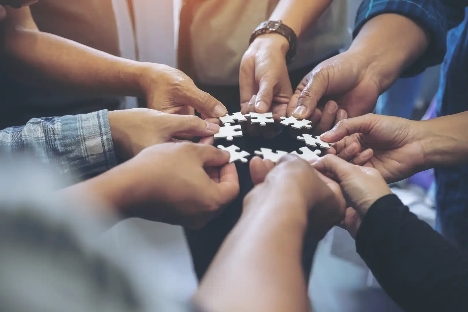 Team members' hands joining puzzle pieces together during an Edinburgh team building activity