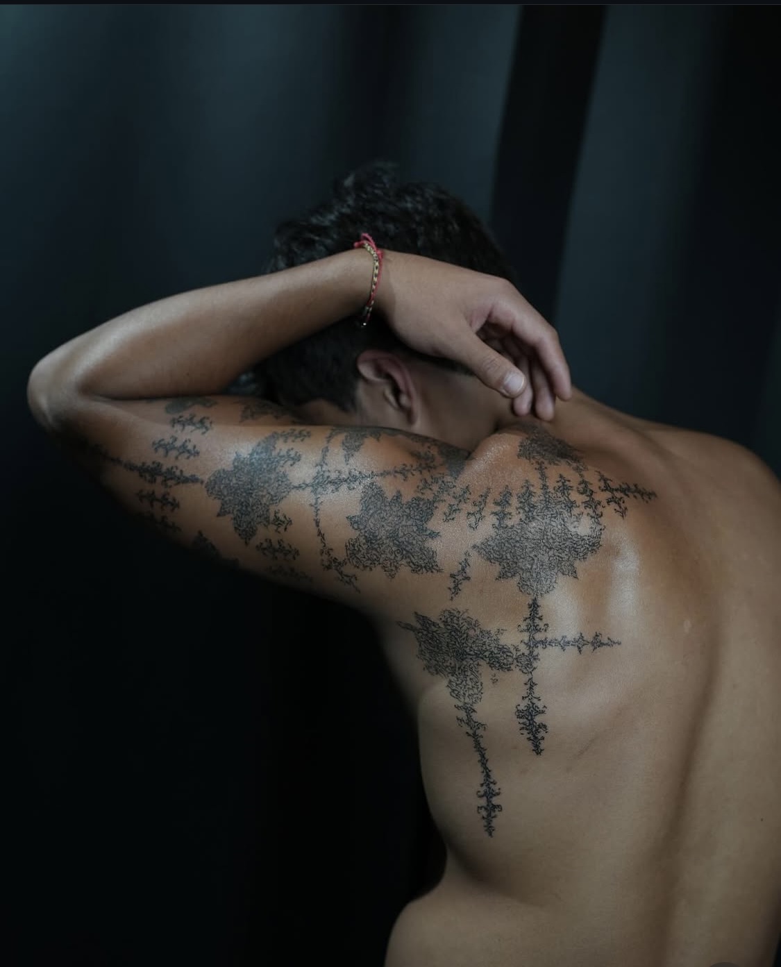 Abstraktes Wirbelsäulen-Tattoo, das den Rücken hinunterfließt, bei Transparent Plattform in Berlin.