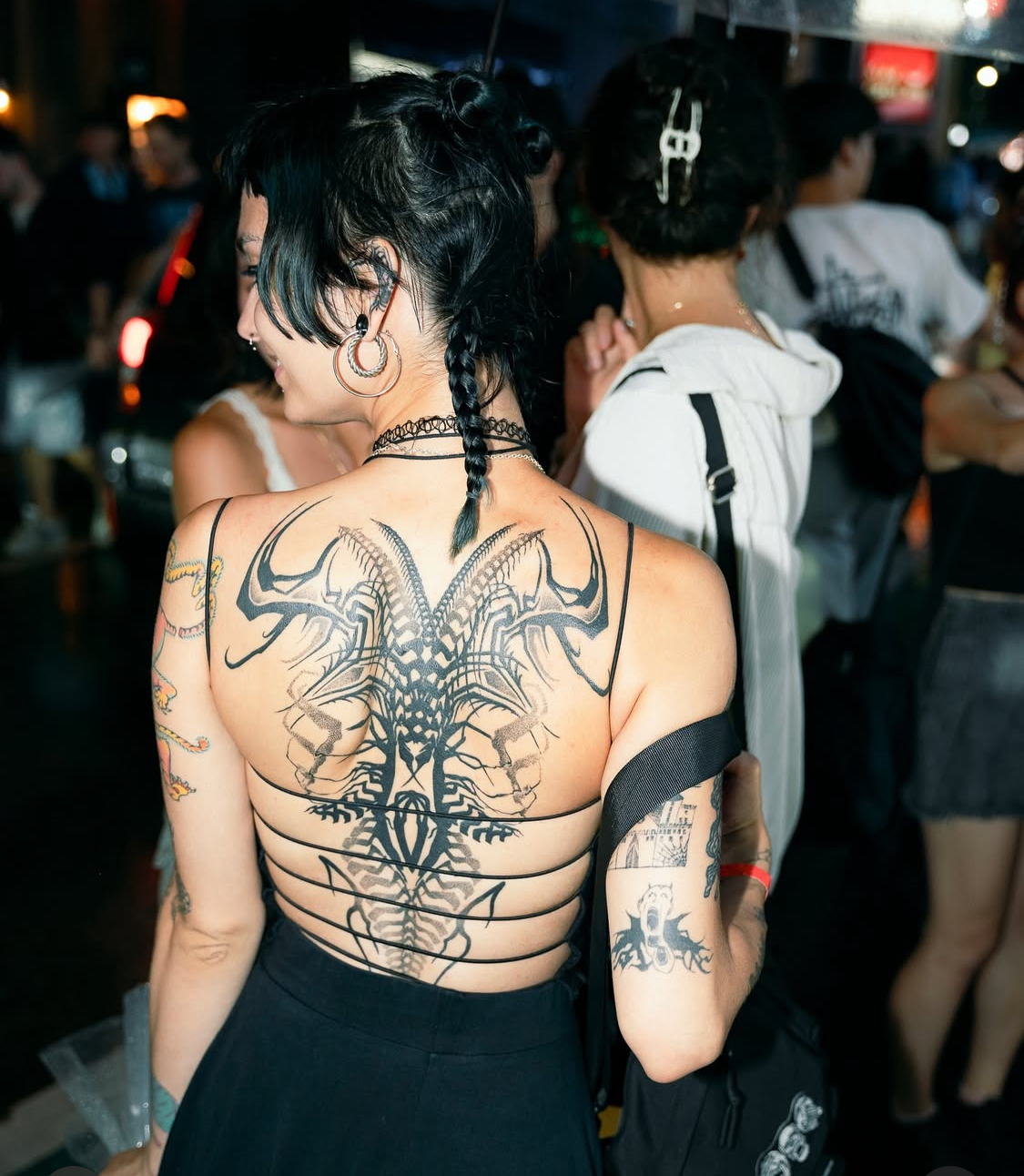 Abstraktes Wirbelsäulen-Tattoo, das den Rücken hinunterfließt, bei Transparent Plattform in Berlin.
