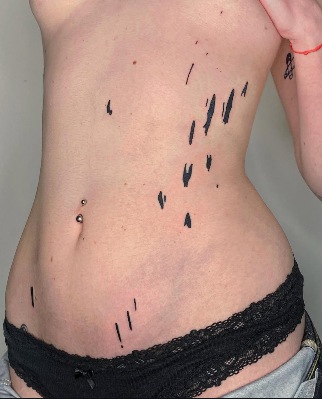 Minimalistisches Tattoo mit blauer Tinte entlang der Rippen.