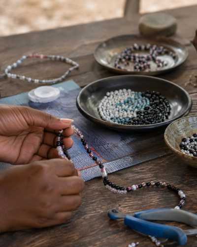Hands threading beads at a jewellery-making class in Namibia