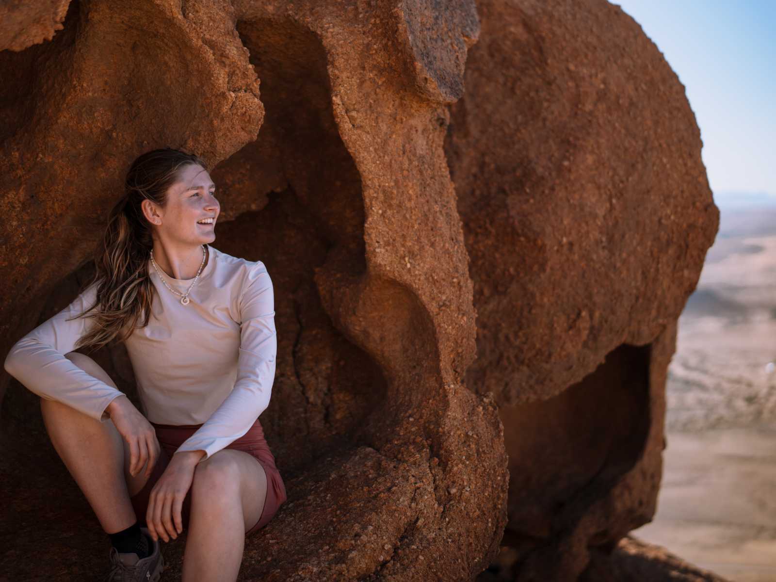 Woman sitting inside a rock arch at Spitzkoppe, Namibia