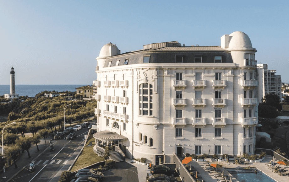 Bâtiment hôtelier de style classique face à l’océan avec terrasse et vue côtière