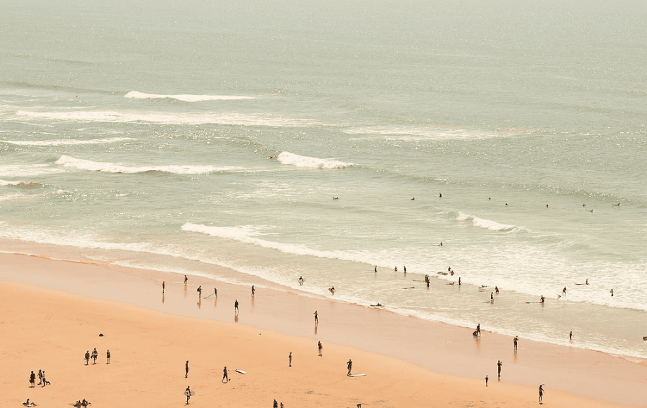 Une vue aérienne épurée d'une vaste plage de sable fin et d'un océan aux teintes pastel.