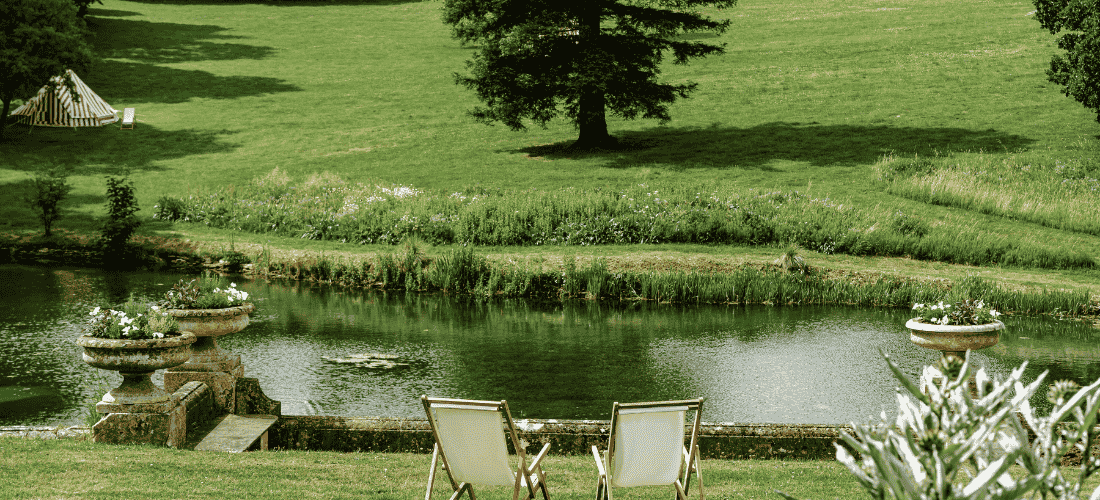 Deck chairs by a peaceful garden pond surrounded by greenery