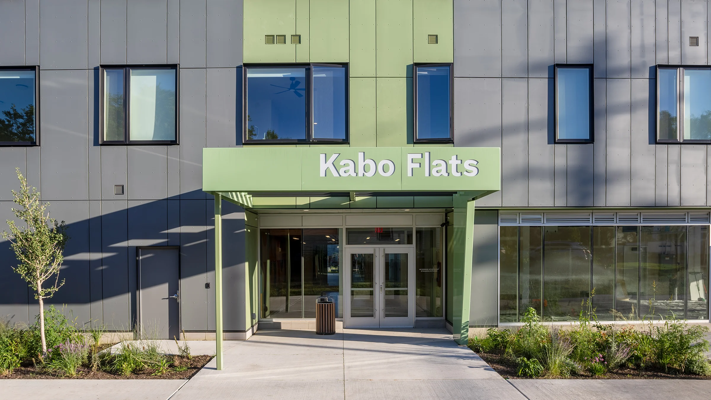Face of the Kabo Falts apartment building. Green entryway and gray facade.