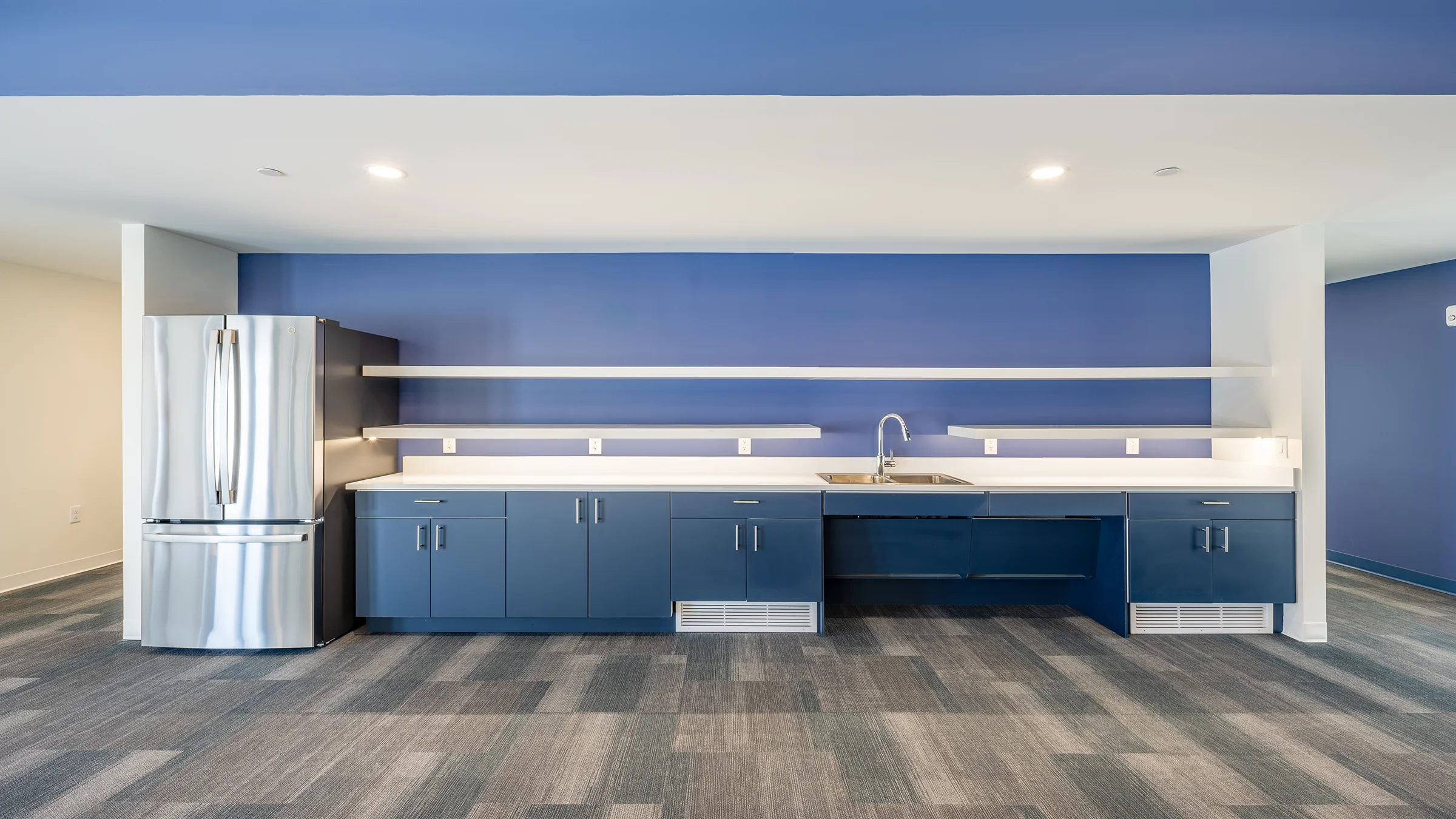 Shared kitchen area and open space at Kabo Flats. Blue cabinets and wall colors with white countertops.