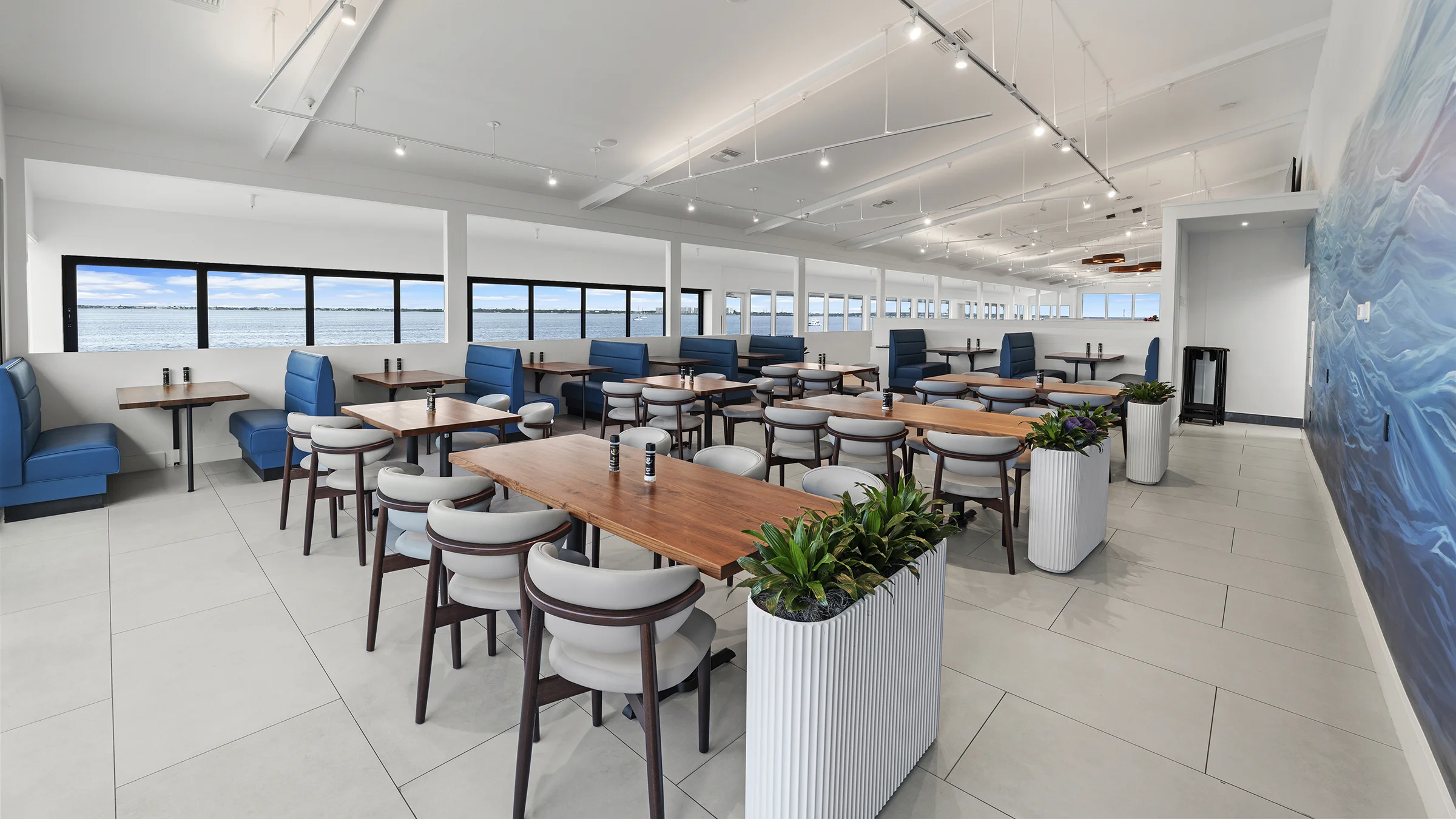 Latitude 26 restaurant interior with blue booths, plant fixtures and a blue ocean mural on the wall.