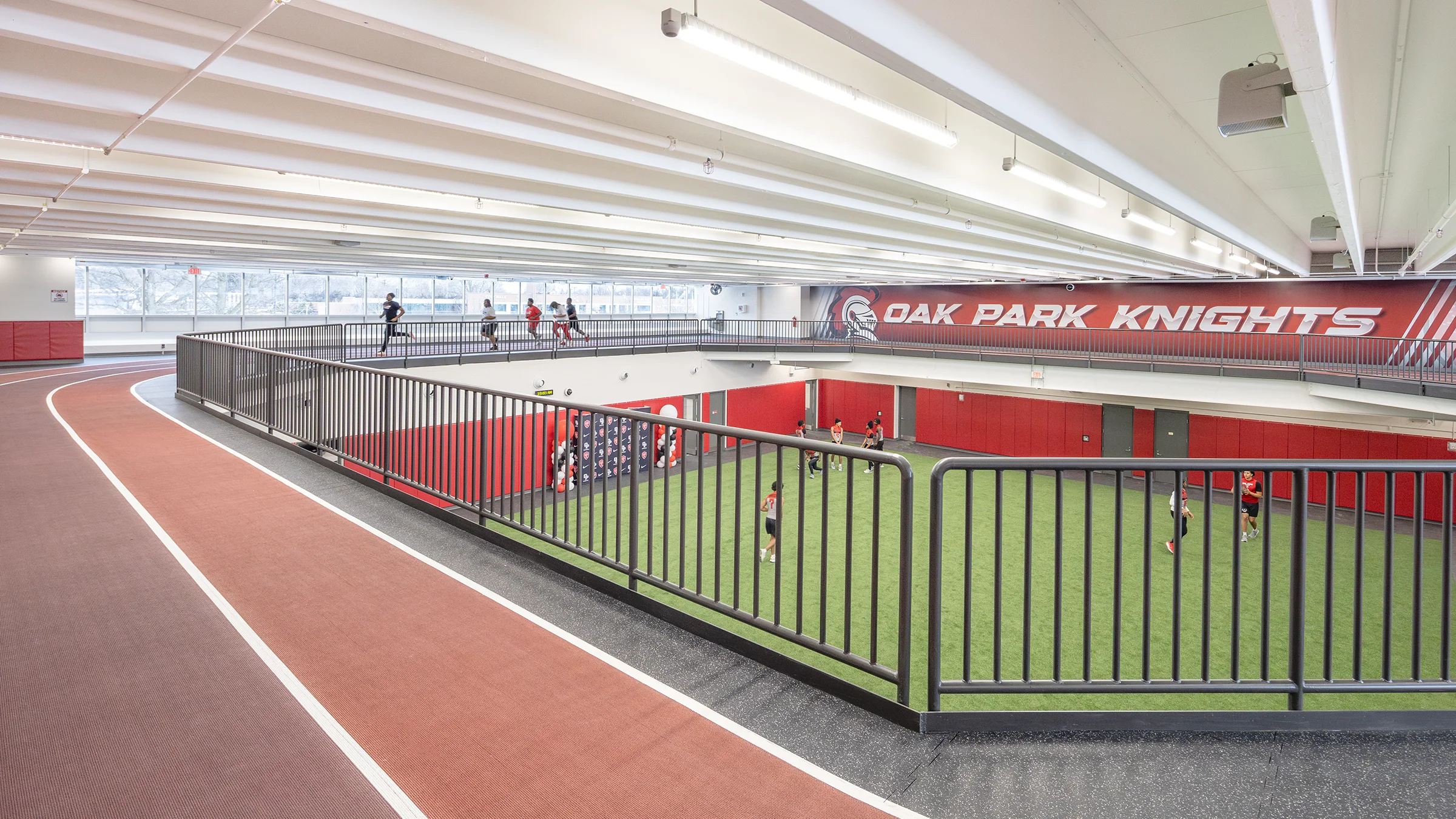 Students running around upper-level track above turf field.