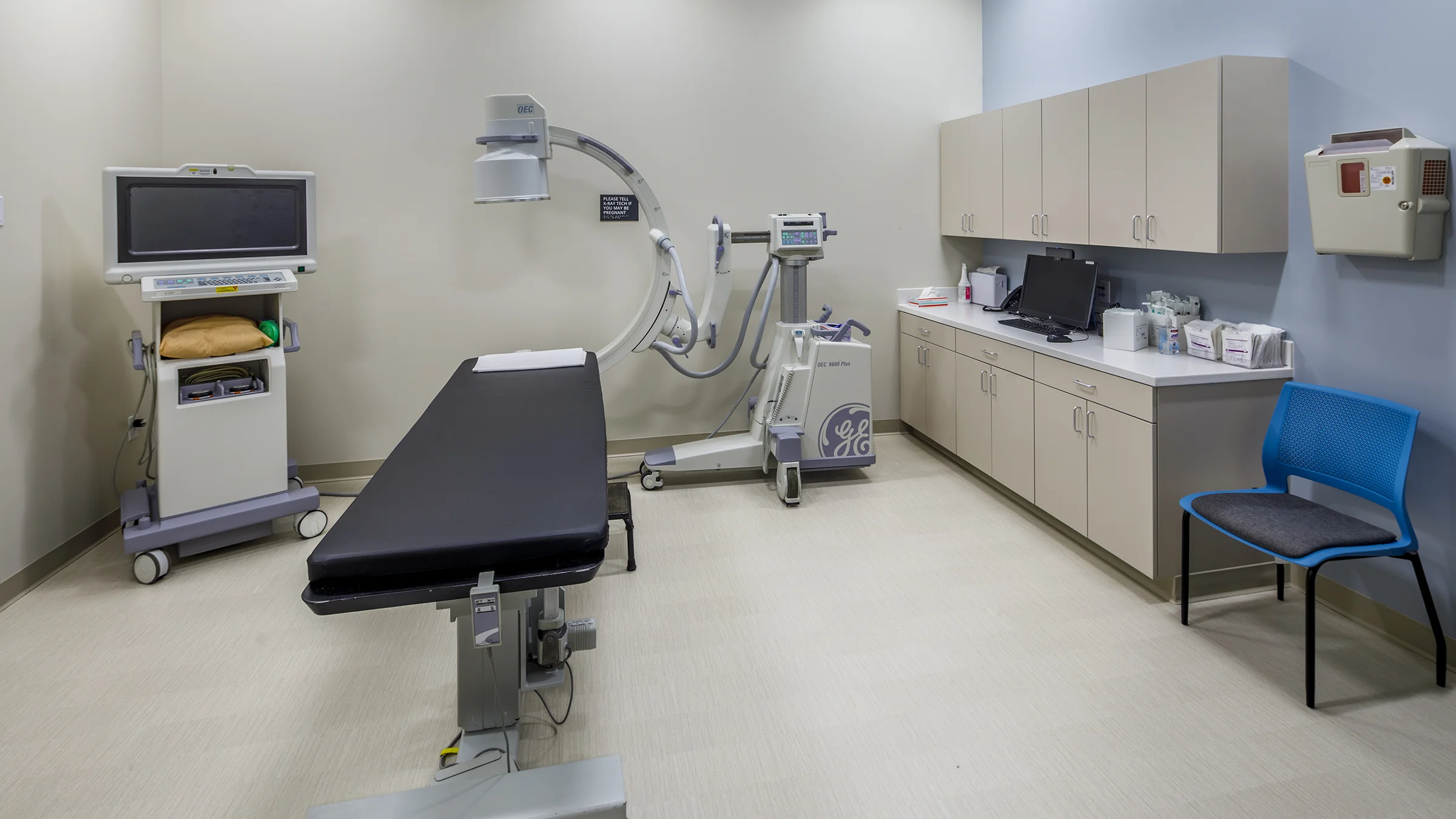 Examination room with table and X-ray machine.