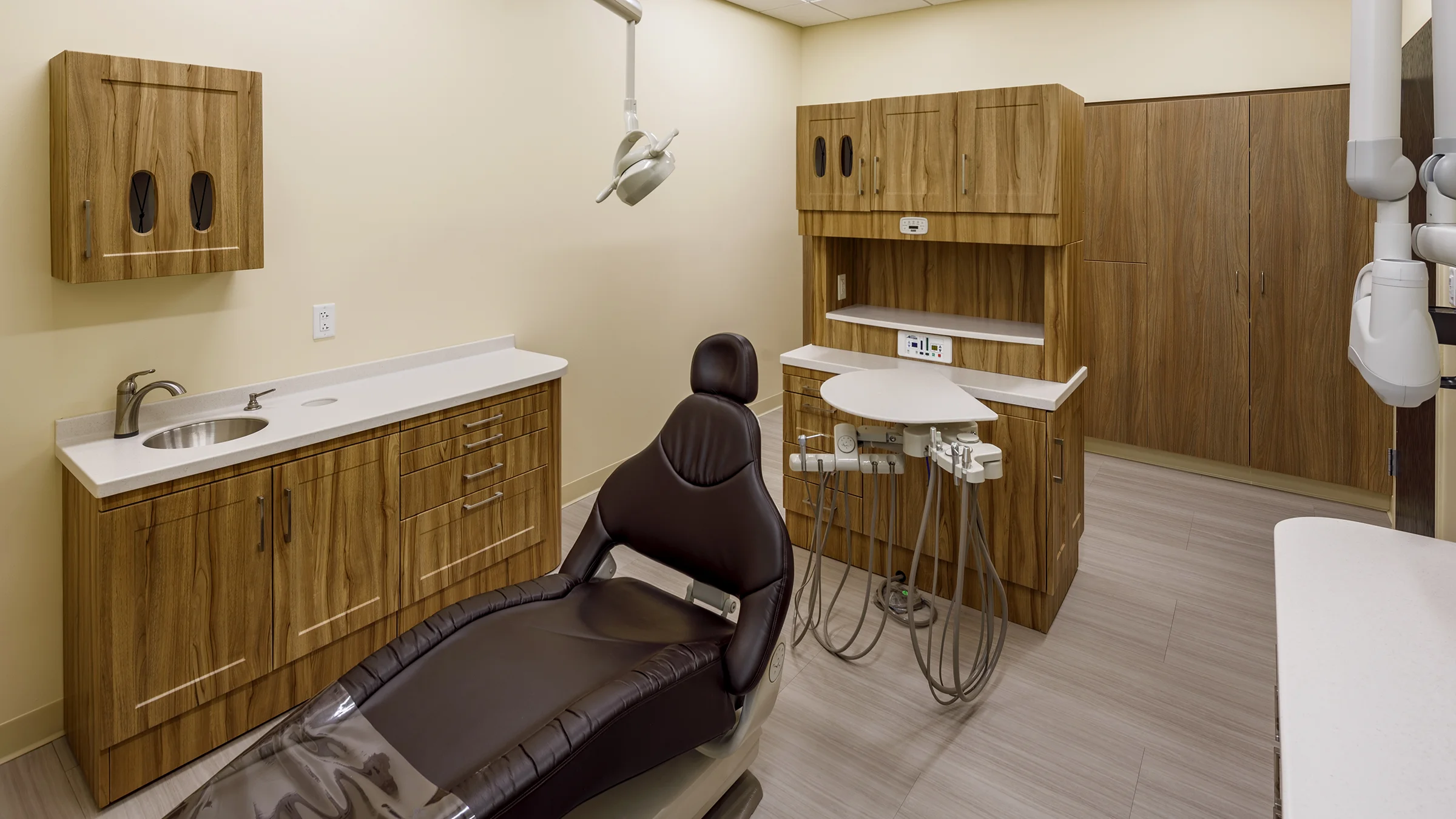 Dentist chair in Covenant Community Care's Joy Road Clinic. The office features yellow walls and warm wood cabinetry.