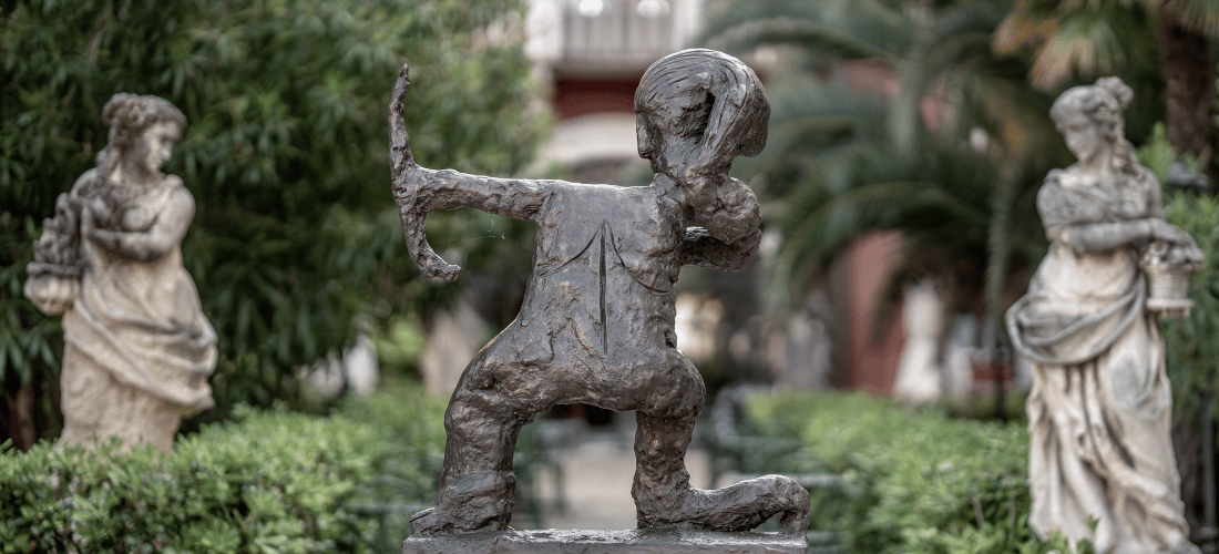 Historical statues surrounded by lush tropical greenery at a palazzo in Italy