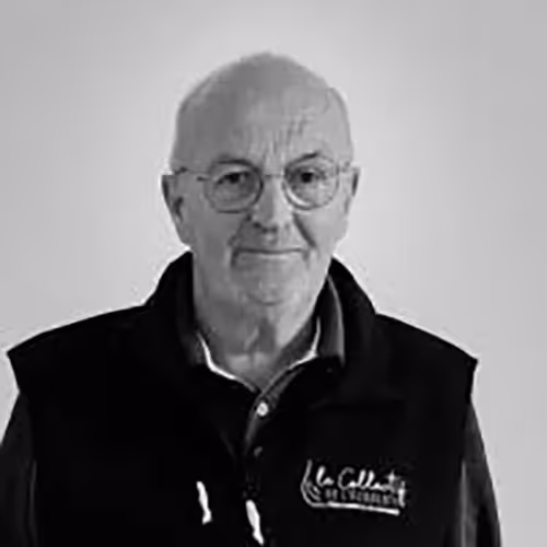 Portrait en noir et blanc d’un homme âgé portant des lunettes et un gilet floqué La Colloc de Locoal.