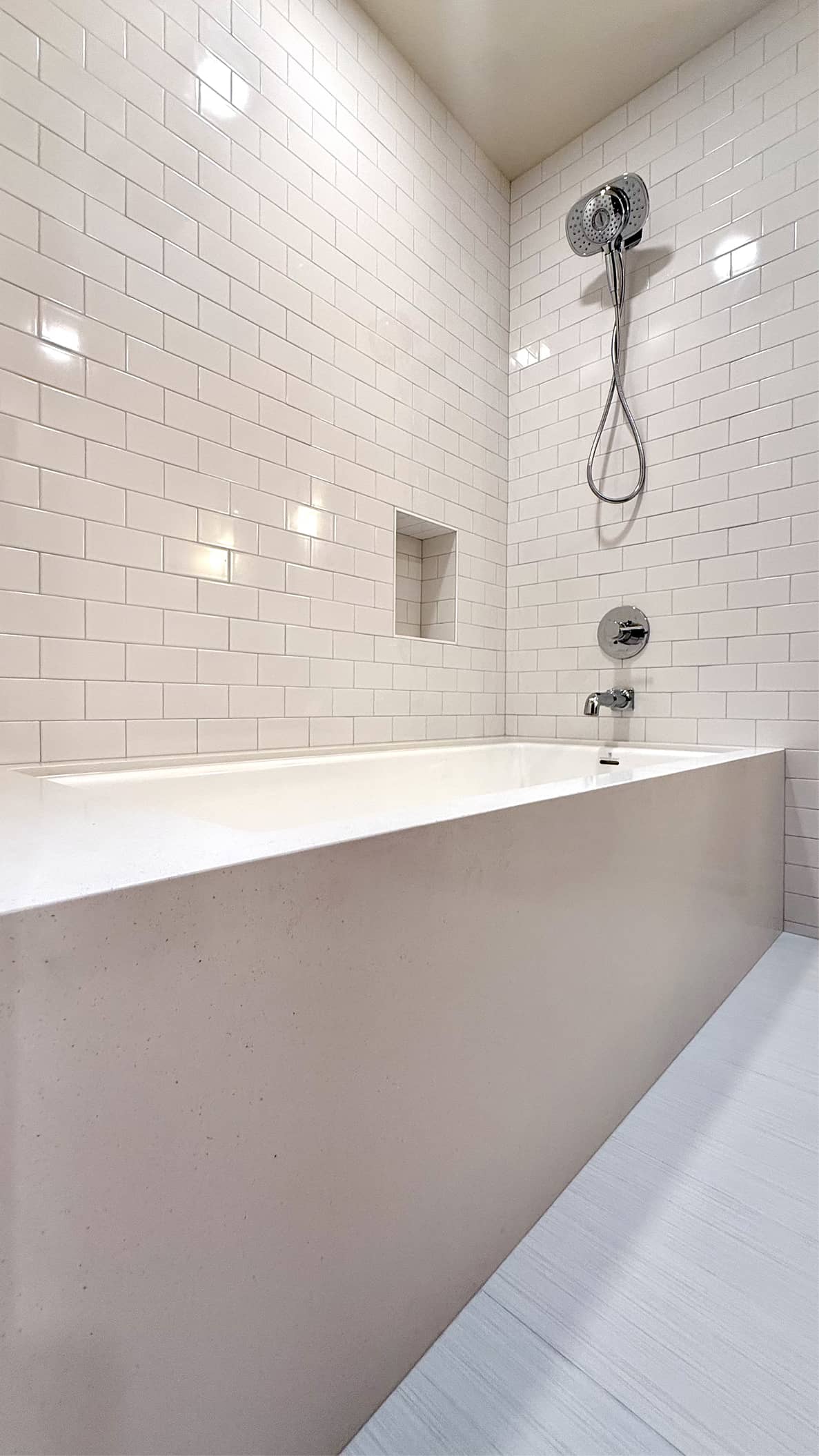 Tub-shower combo with white subway tile surround and recessed niche by NBE LLC\
