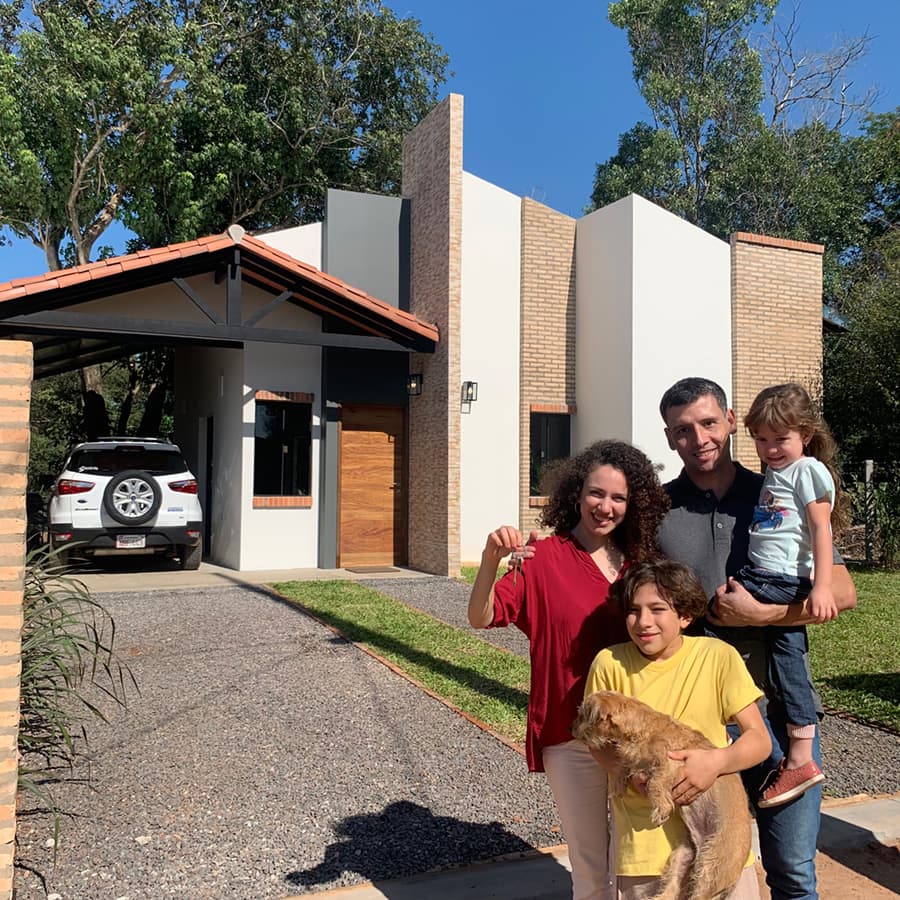 Familia en frente a su nueva casa más, mamá mostrando la llave