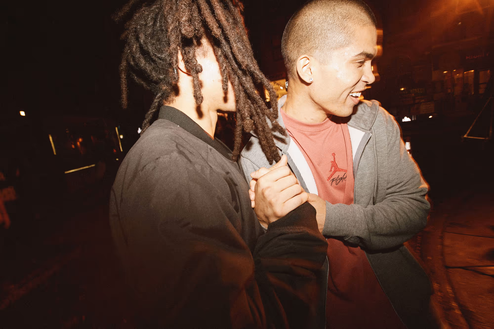 A spectator wearing a #8 Pence baseball jersey walking down a stadium concourse at night, with other fans and bright stadium lights in the background.