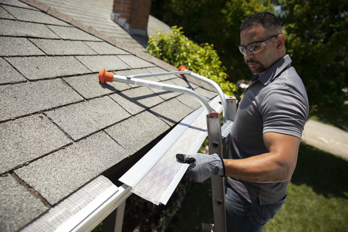 A worker installing gutter guards on a residential gutter system