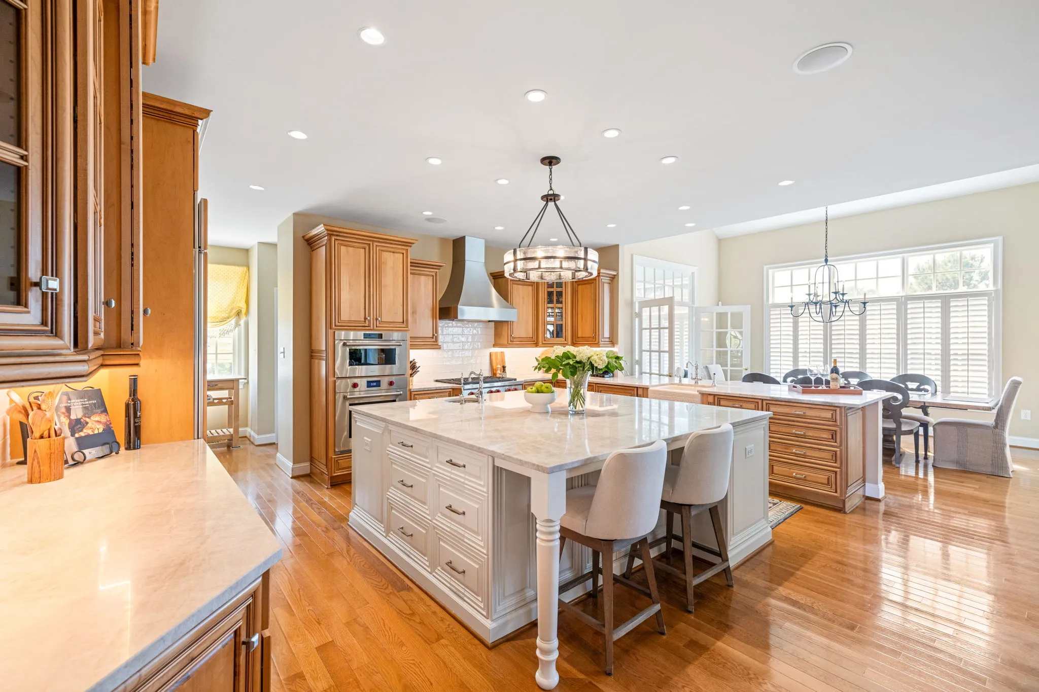 Luxury traditional kitchen with large island, wood cabinetry, marble countertops, and stainless steel appliances