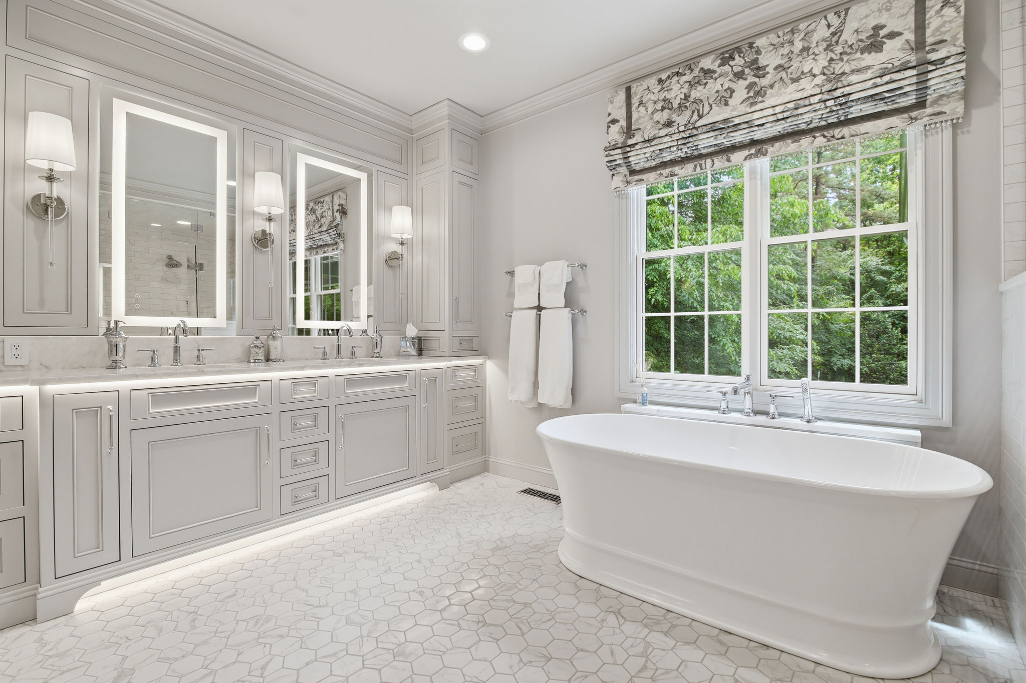 Custom primary bathroom vanity in Salisbury, Richmond, with gray inset cabinetry, illuminated mirrors, sconces, under-cabinet lighting, and hex tile flooring.