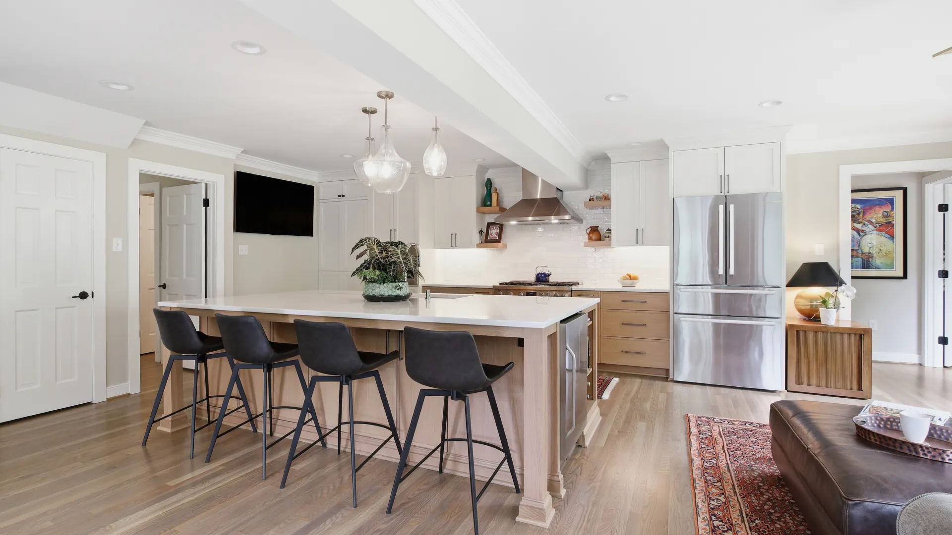 Bright remodeled kitchen in Tuckahoe, Richmond featuring a large white quartz island, warm white oak cabinetry, white perimeter cabinets, stainless steel appliances, and an open layout designed for first-floor living.