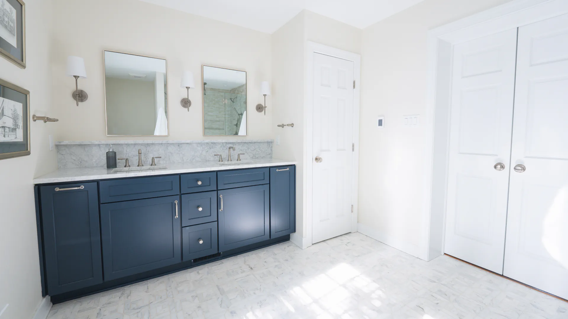 Bright primary bathroom in a Salisbury first-floor suite addition featuring a navy double vanity, marble countertop, dual mirrors, and polished nickel fixtures.