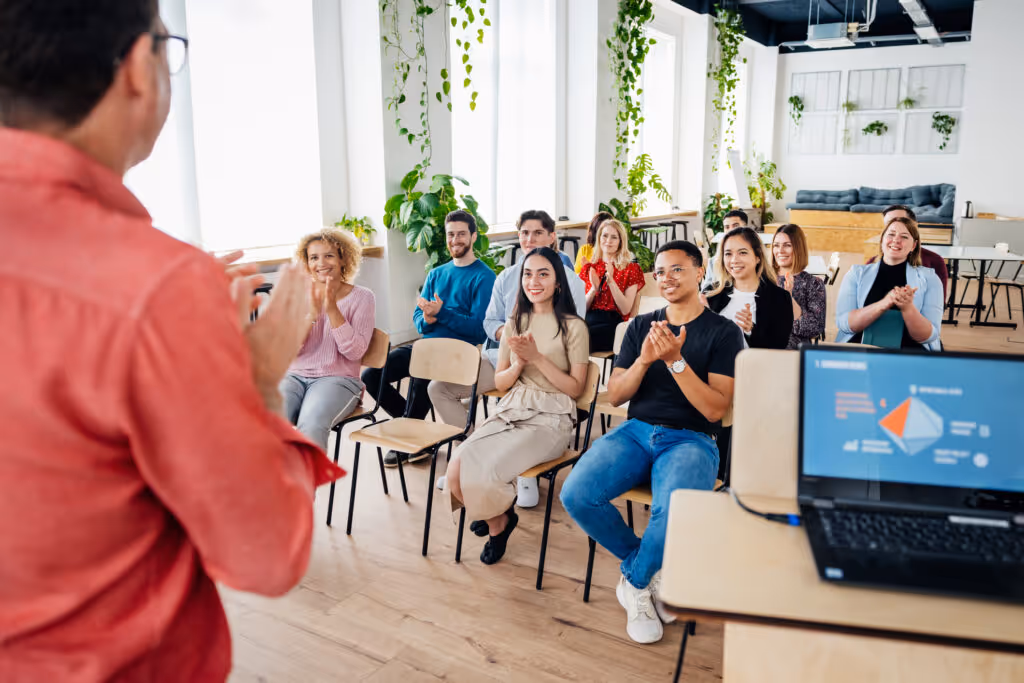 An audience sitting down and applauding the host after watching a presentation together during a seminar session.