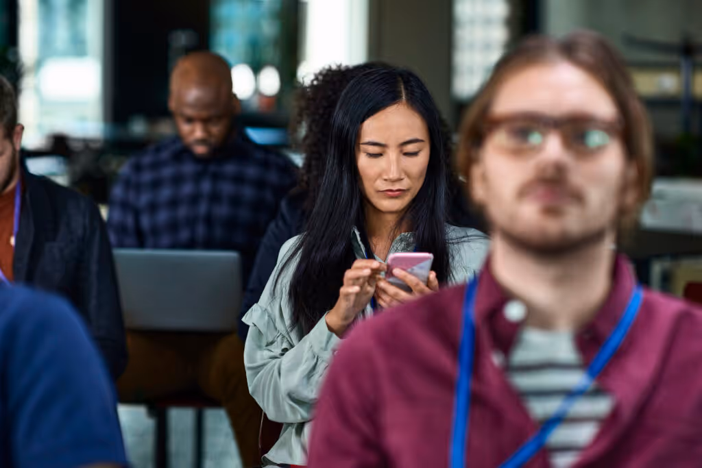 Businesswoman checking her smartphone at a team meeting.