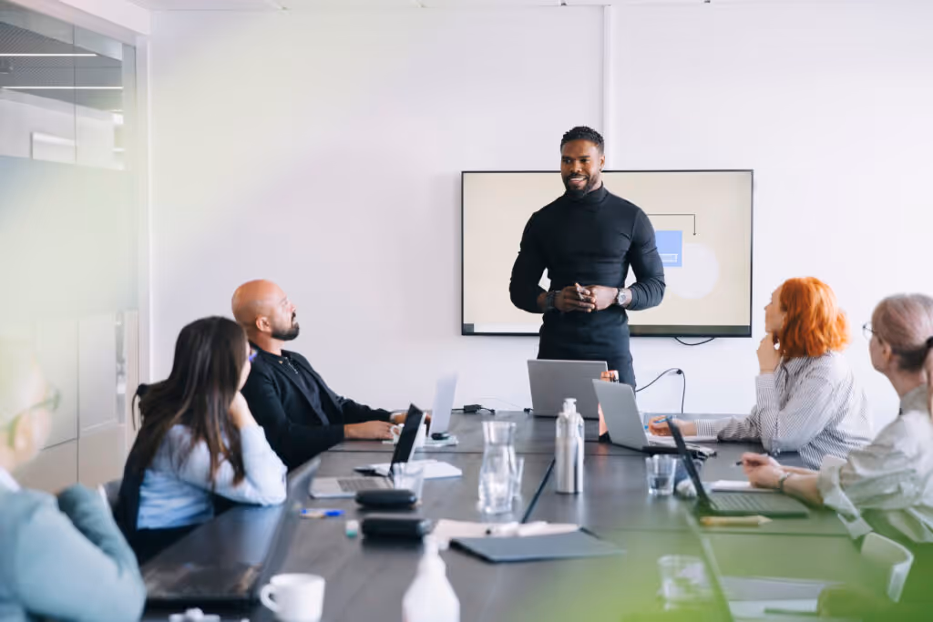 Male professional sharing business strategies with colleagues in board room