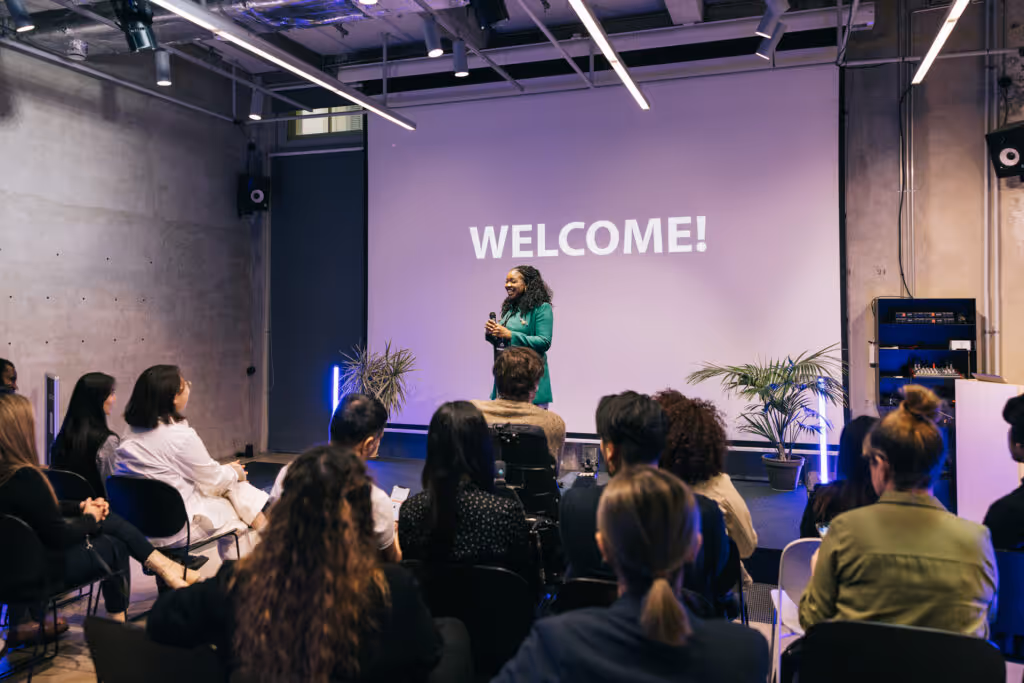 Against the backdrop of a startup tech conference, a business entrepreneur takes the stage, delivering an impactful presentation. Their confident posture and charismatic delivery hold the audience's attention.