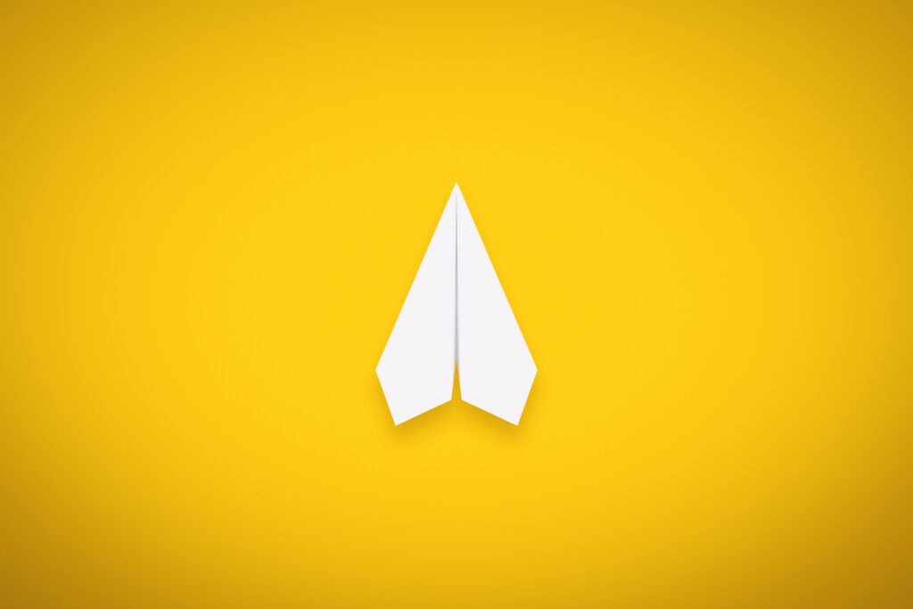 A Single Paper Airplane on Yellow Background