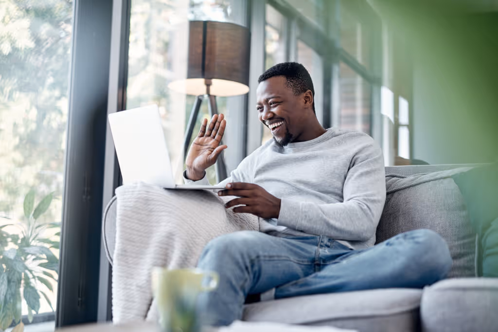 Shot of a young man using a laptop to make a video call on the sofa at home