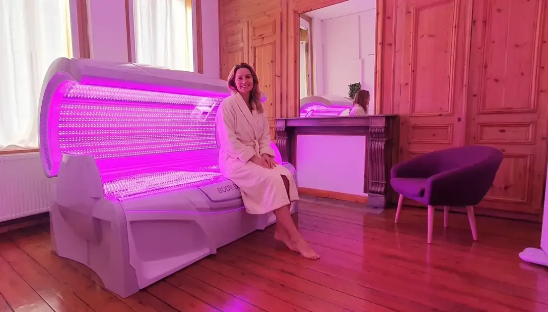 Une cliente souriante assise sur le Body Boost Bed illuminé, au centre Luminecla à Lille