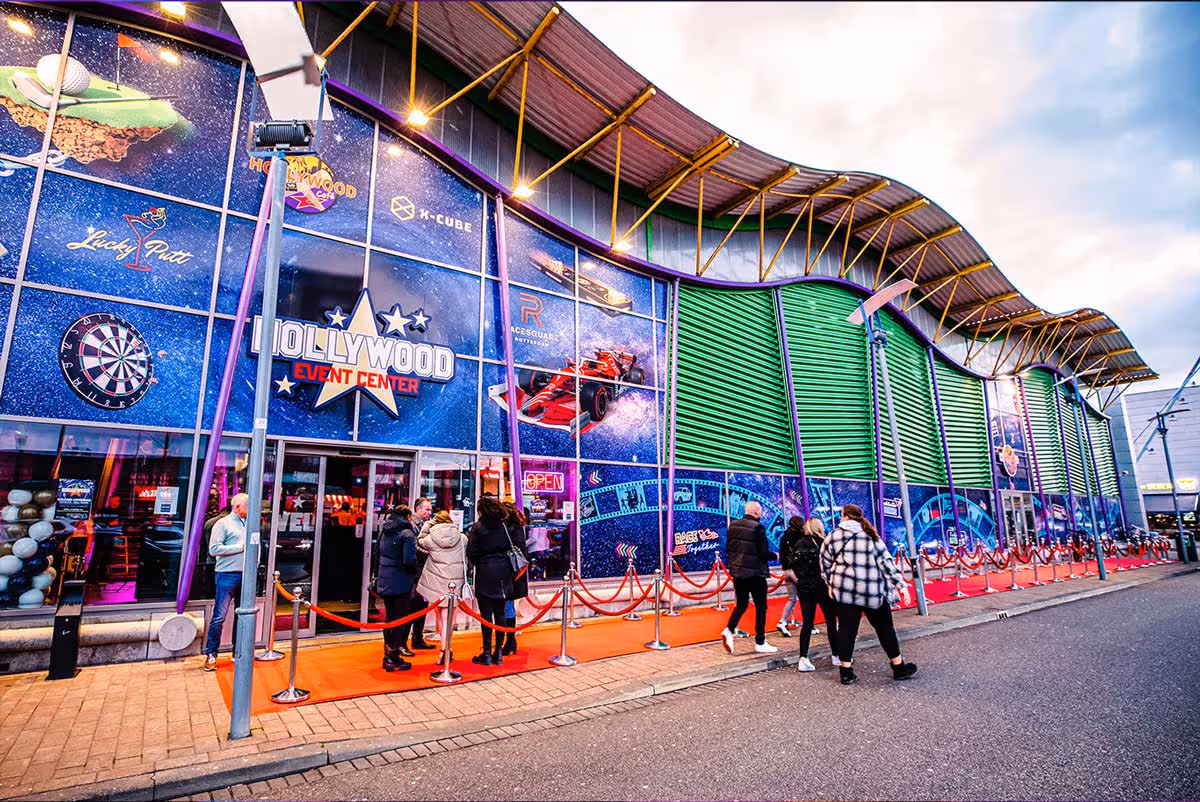 Hollywood Rotterdam. Exterior of Hollywood Event Center featuring a colorful facade with game-themed graphics and people walking and queuing outside.