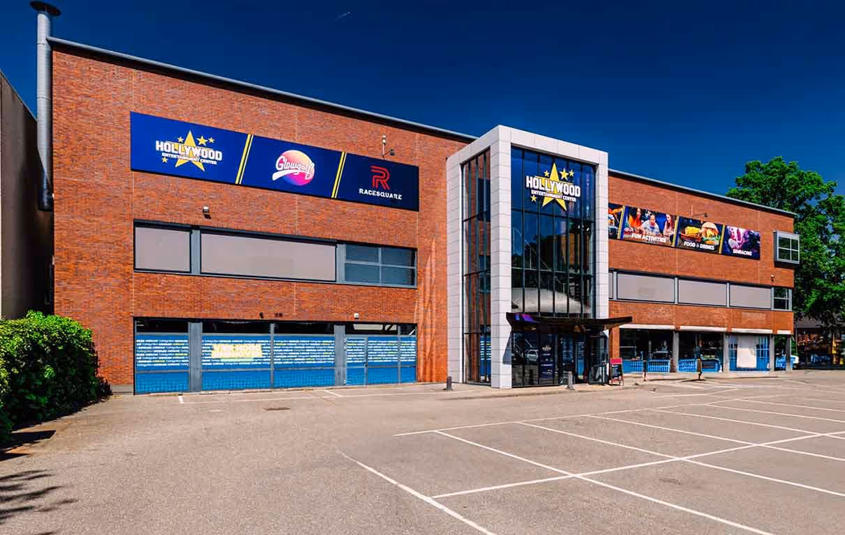 Buitenzijde van Hollywood Entertainment Center Utrecht met moderne glazen entree, parkeerterrein en gevelborden van entertainmentactiviteiten.