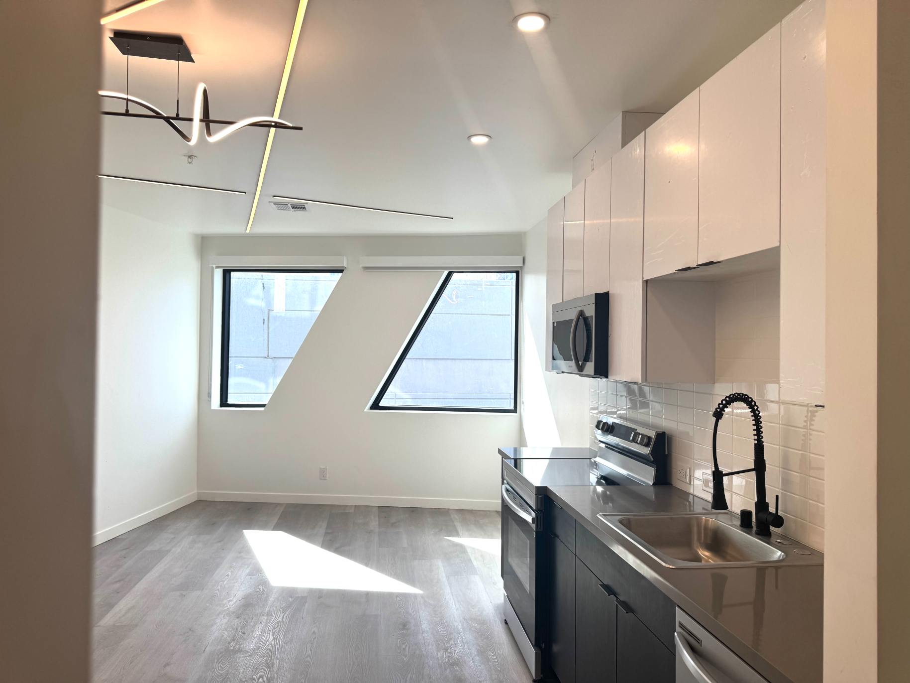 Modern kitchen with a black island, white cabinets, and large windows in an apartment at Rainbow Road in Phoenix, AZ