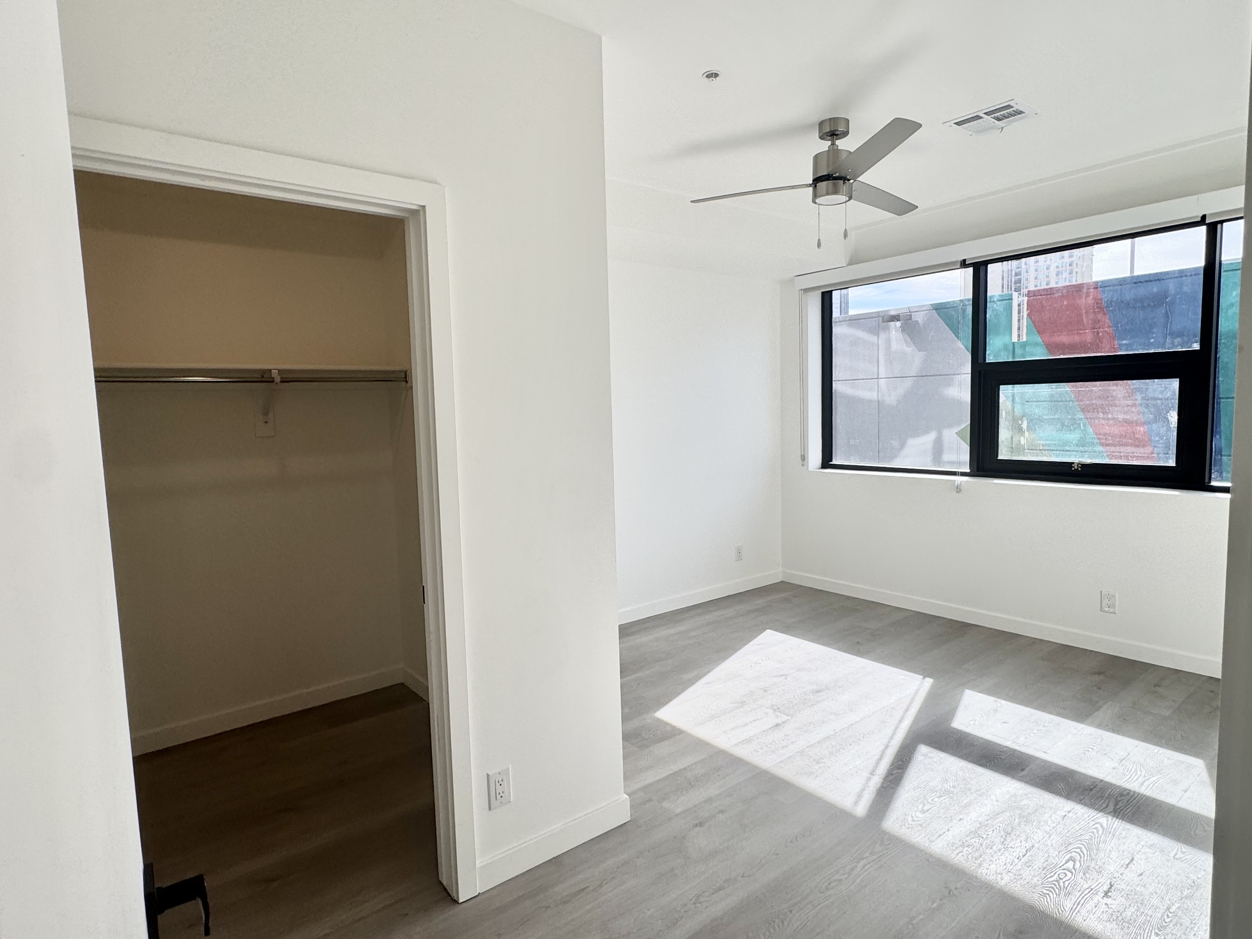 Spacious bedroom with white walls and large windows offering city views from an apartment at Rainbow Road in Phoenix, AZ.