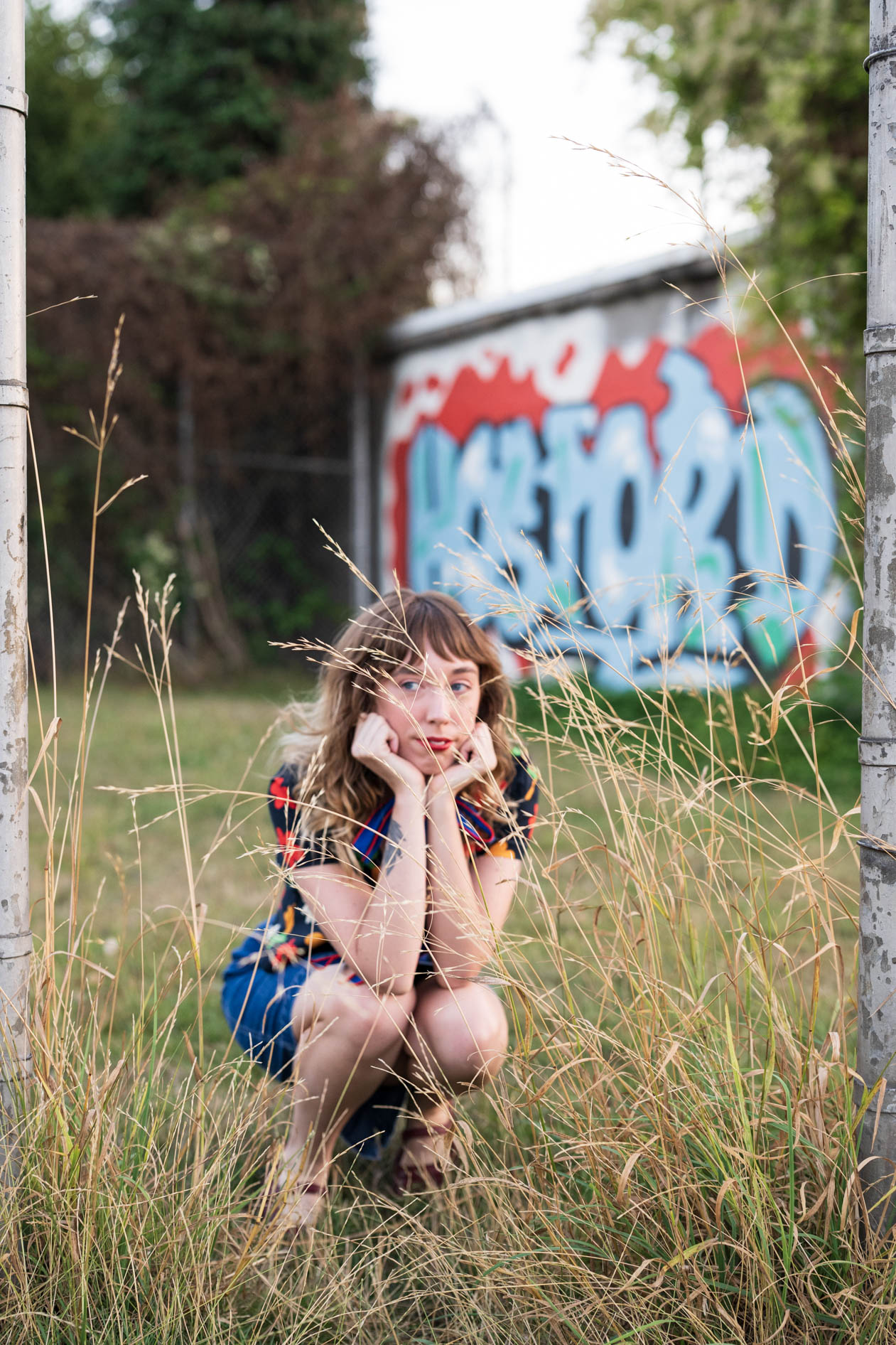 kayla crouches in some grass outside in portland