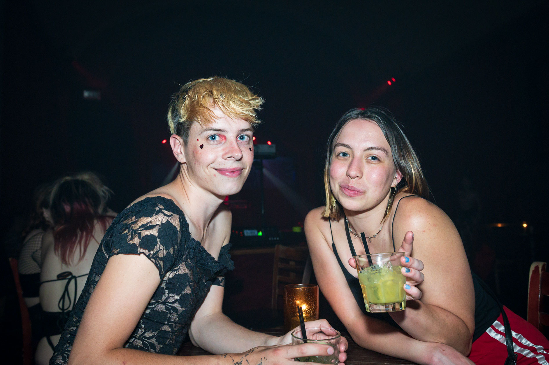 two sweet friends pose with their drinks at a table in downtown Portland