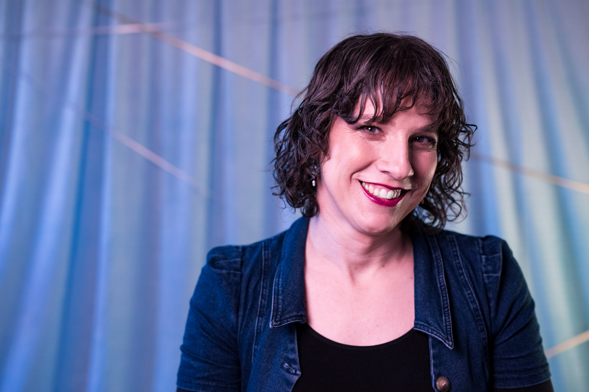 a beautiful trans woman poses against a blue backdrop