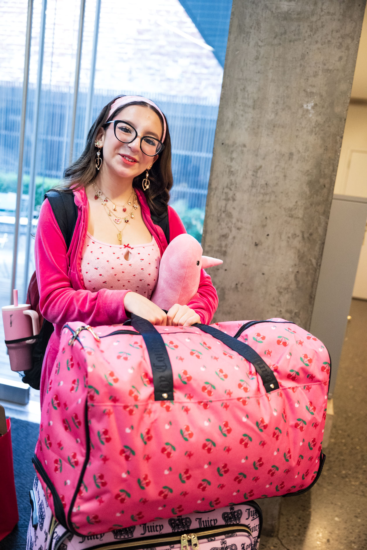 a PNCA student in a bright pink outfit carries their bags into a downtown Portland dorm