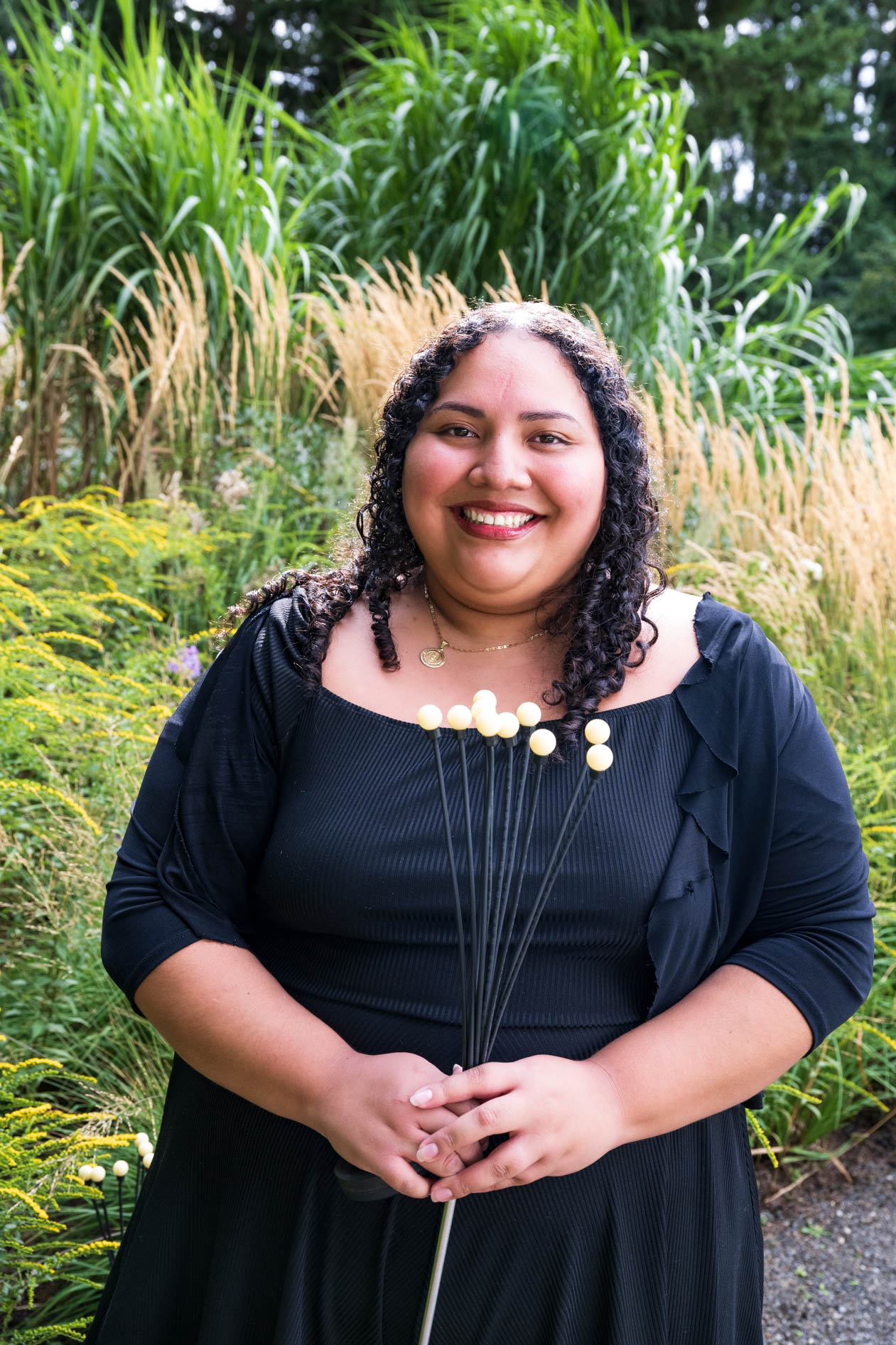 A joyful woman smiles at the camera while holding a unique bouquet at the Feast in the Garden event in SE Portland.