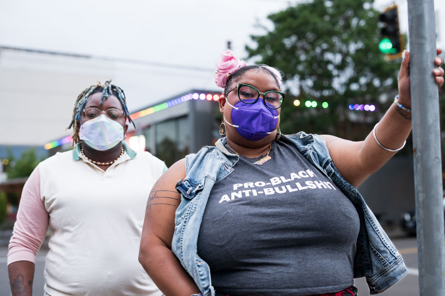 A commercial photograph of two people with masks and glasses, posing together on a street corner. This image is for a case study about a T4T pride photoshoot for Affect, featuring trans and disabled models in Portland, Oregon.