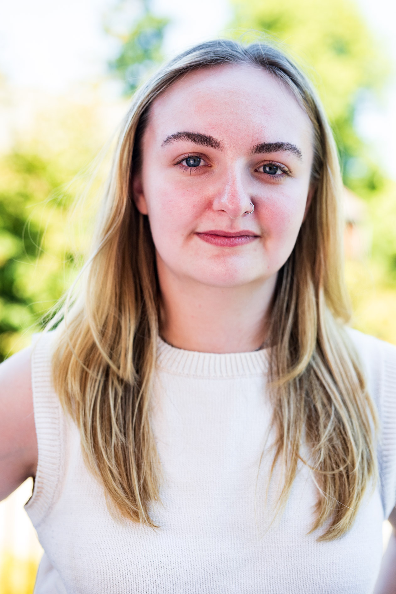 A professional and authentic portrait of a smiling person with long blonde hair and a white sweater. This is an example of an inclusive headshot captured for Willamette University in Salem, Oregon.