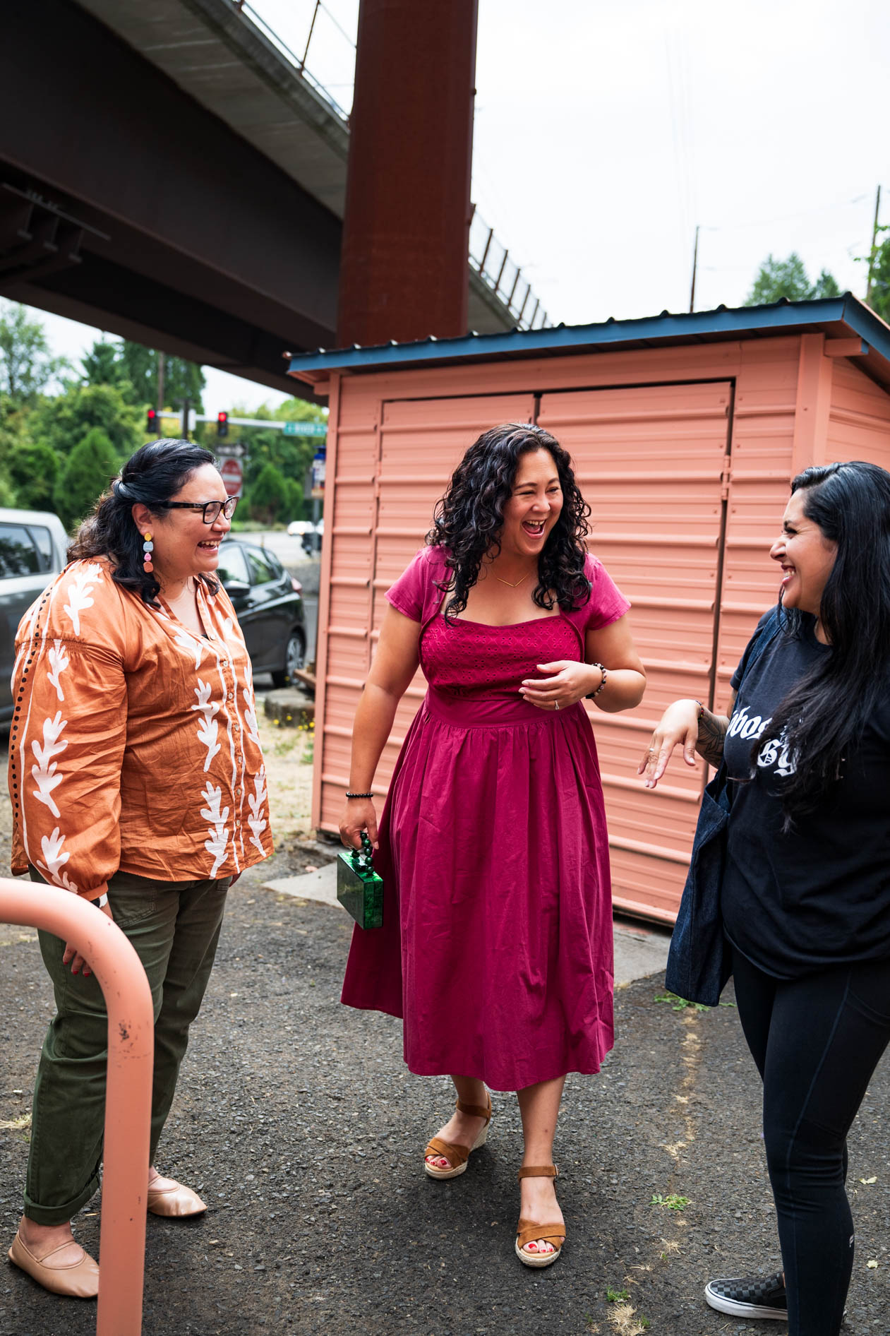 An authentic, candid photograph of three people laughing and talking outdoors. This is an example of commercial photography for a business in Portland, Oregon.