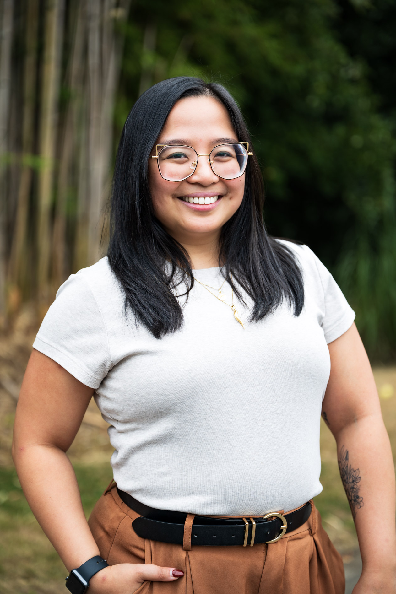 A professional and authentic portrait of a smiling person with glasses, with one hand on their hip. This is an example of commercial photography for a business coaching company in Portland, Oregon.