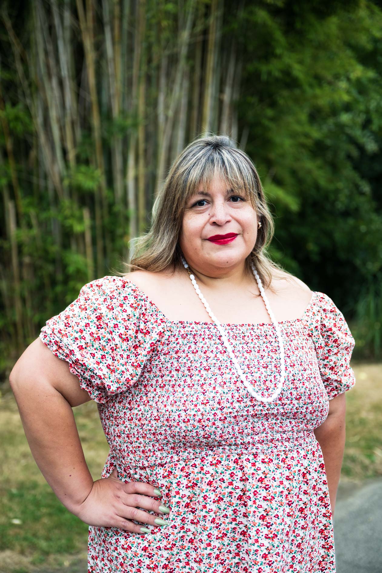 A professional and authentic portrait of a person in a floral dress with a red lip, posing with one hand on their hip. This is an example of commercial photography for a business coaching company in Portland, Oregon.