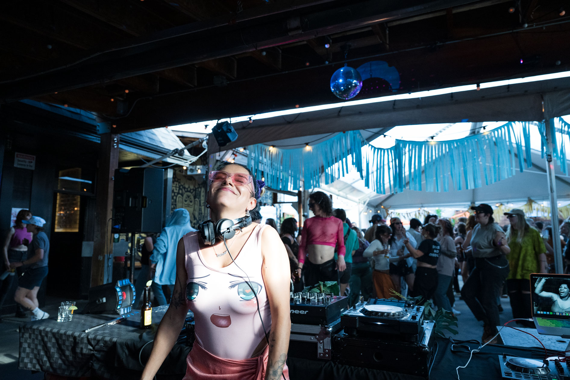 A candid photo of DJ Lapaushi dancing with her eyes closed, with a disco ball hanging in the background. This is an example of commercial photography for an artist's portfolio.