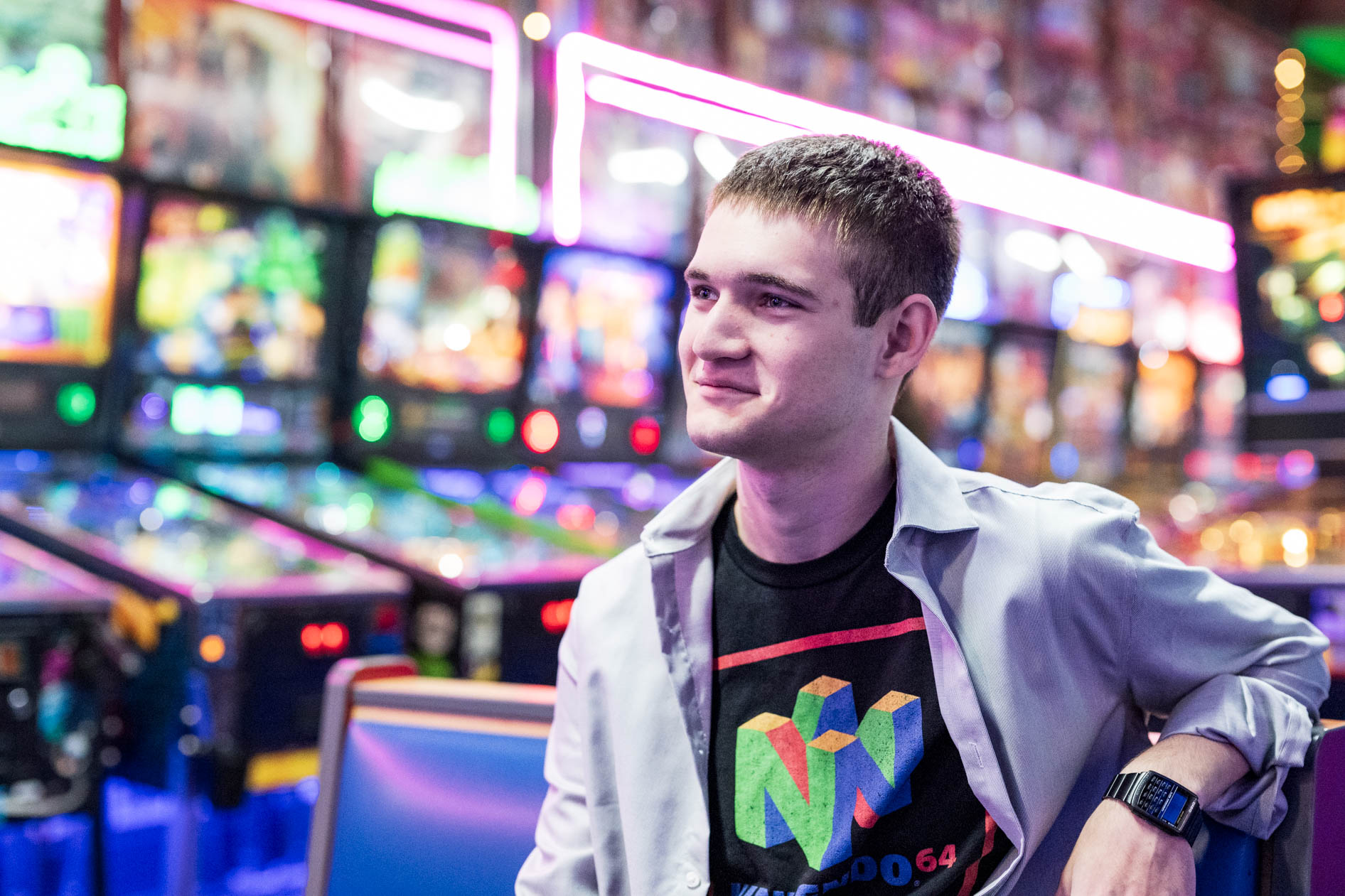A candid senior portrait of a young person smiling in a brightly lit arcade in Hillsboro, Oregon.