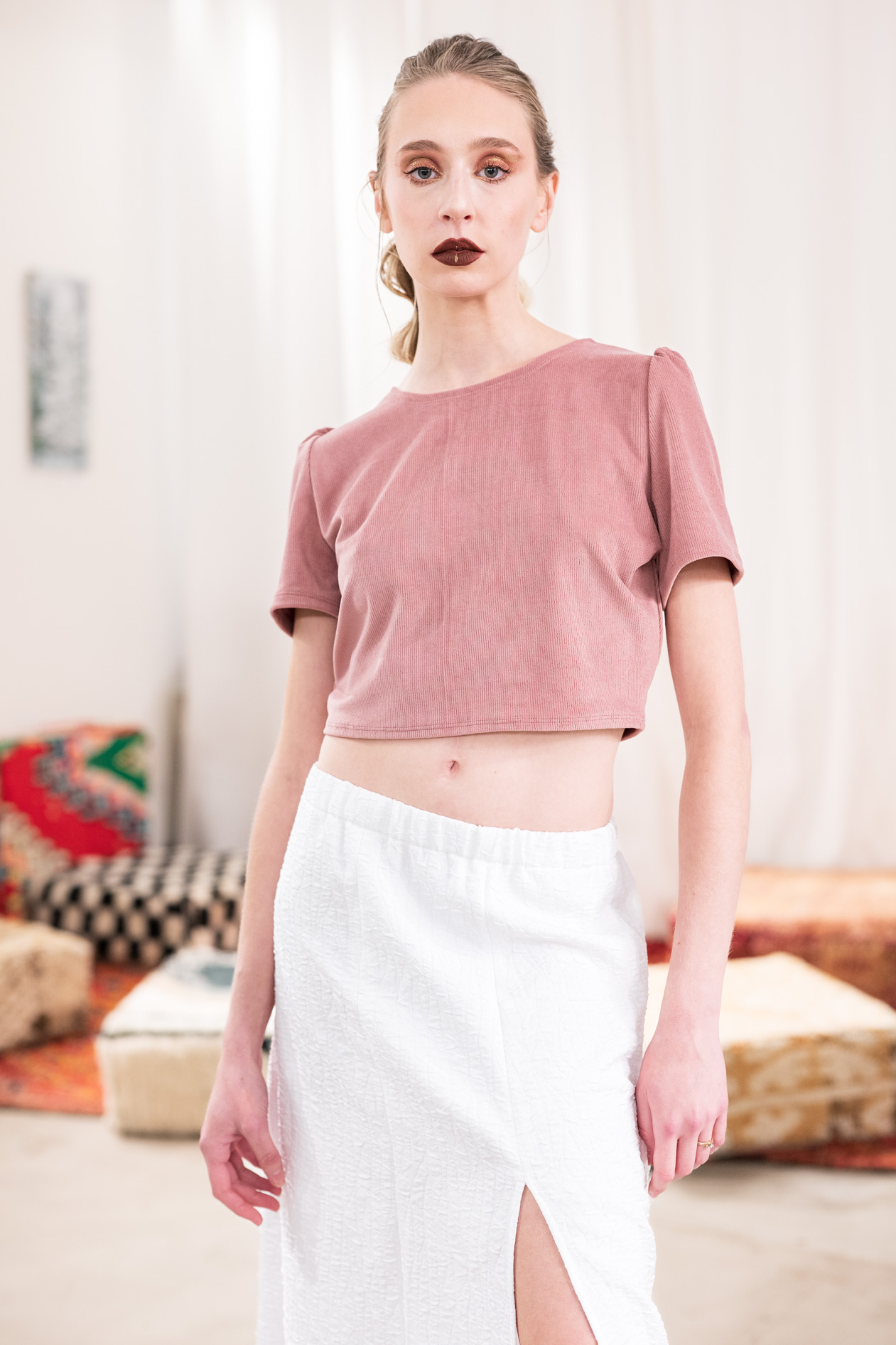 A commercial portrait of a female model wearing a pink crop top and a white skirt with a slit from the boutique brand Ale O. This image showcases lifestyle brand photography in Portland, Oregon.