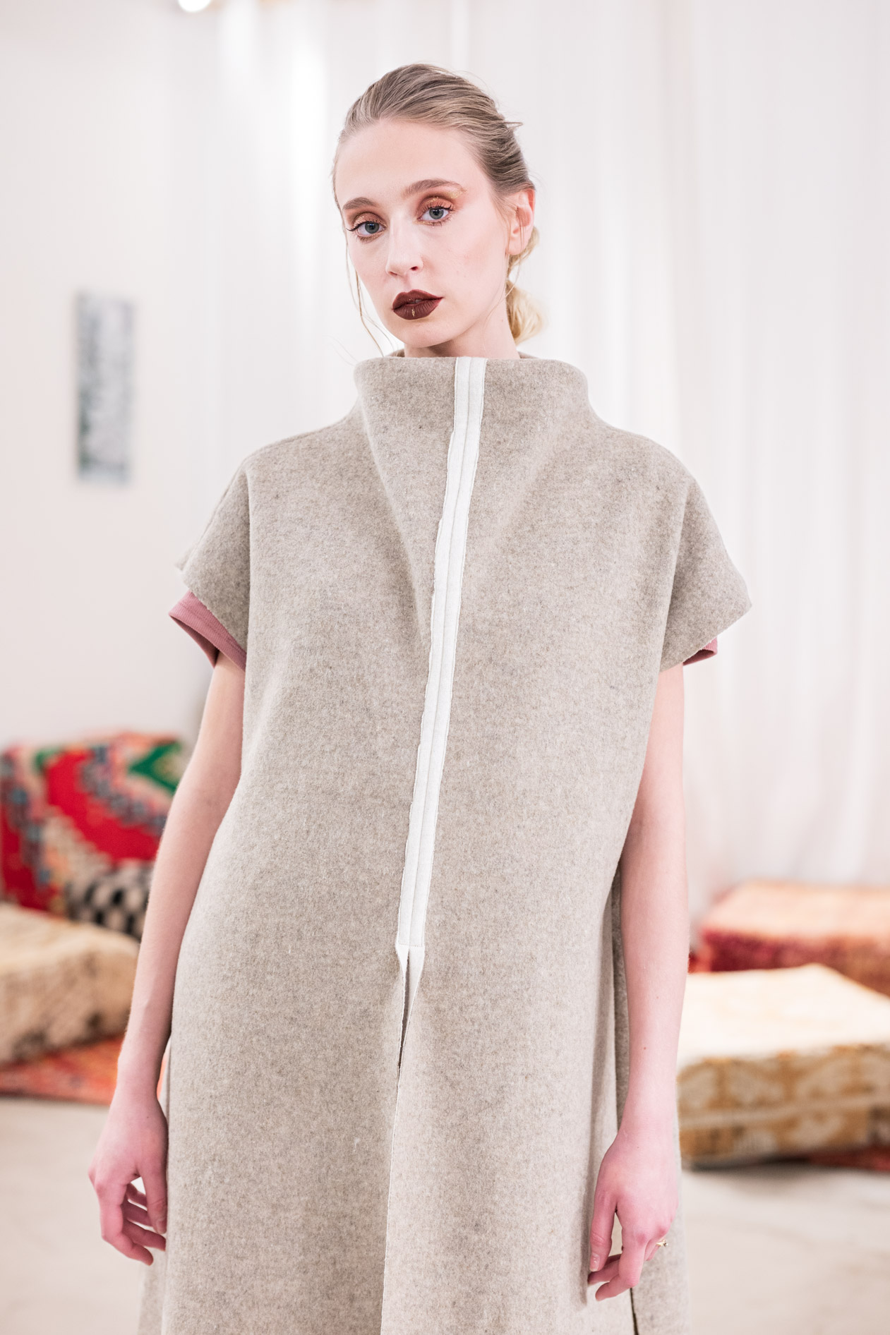 A commercial portrait of a female model wearing a high-collared, sleeveless coat with a white stripe down the front from the boutique brand Ale O. This image showcases lifestyle brand photography in Portland, Oregon.